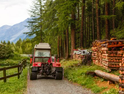Homemade improvised tractor trailer made of strong metal stacked with prepared firewood and covered
