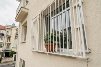 Grillage de protection installé sur une fenêtre en étage élevé d'un immeuble résidentiel urbain