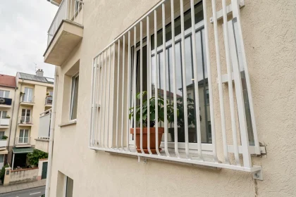 Grillage de protection installé sur une fenêtre en étage élevé d'un immeuble résidentiel urbain